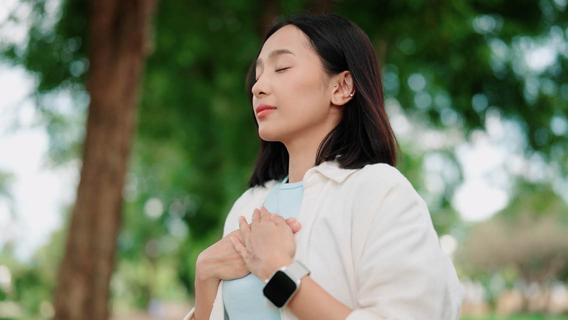 a woman holds her hands over her heart