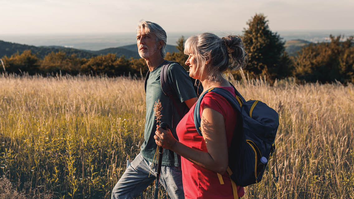 an older couple walks through a field
