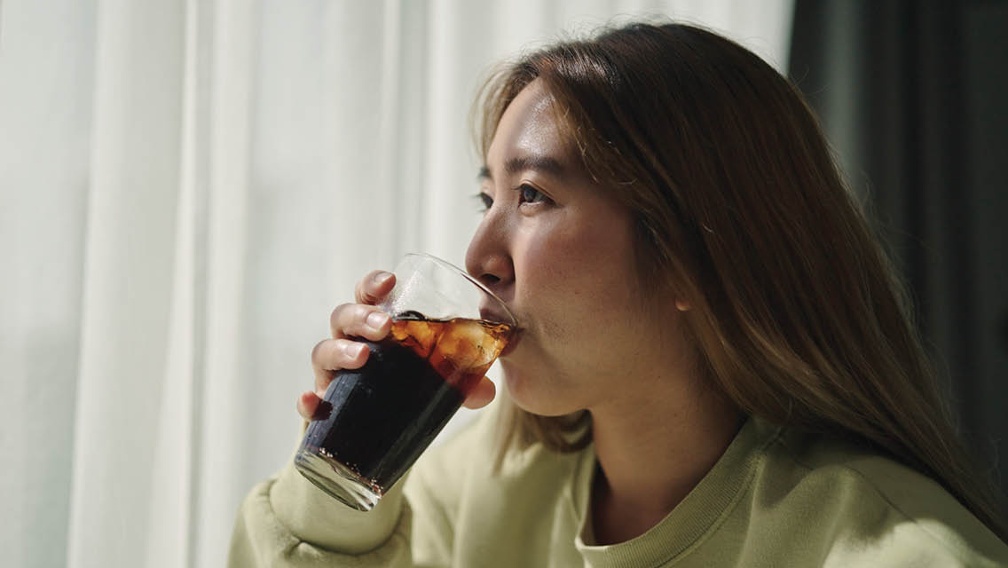 a woman drinks a glass of soda