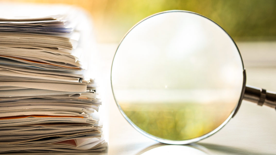 a magnifying glass and stack of papers