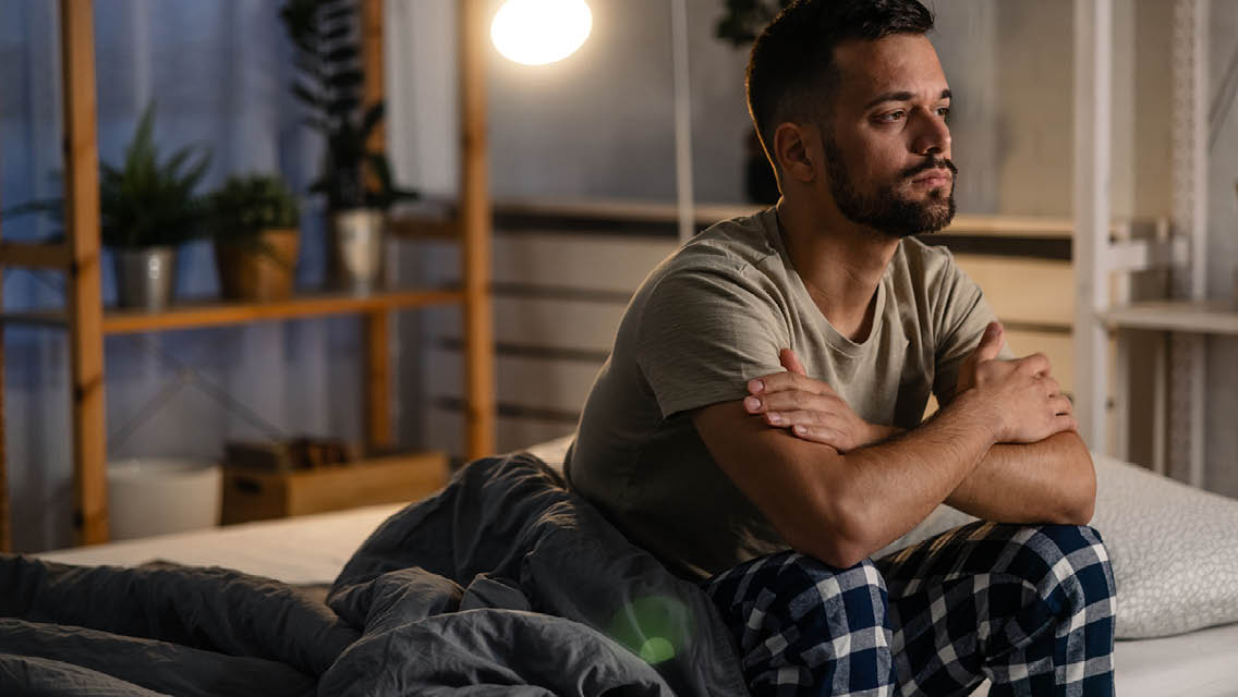 a man sits on the edge of his bed