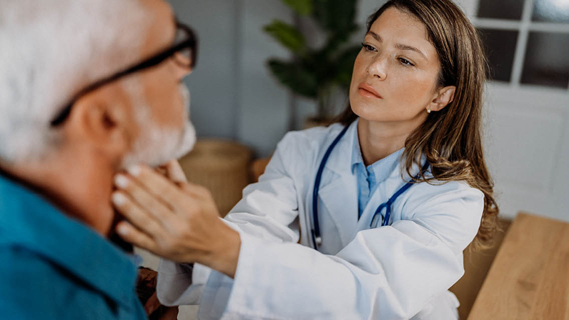 a doctor checks a man's adnoids on his neck