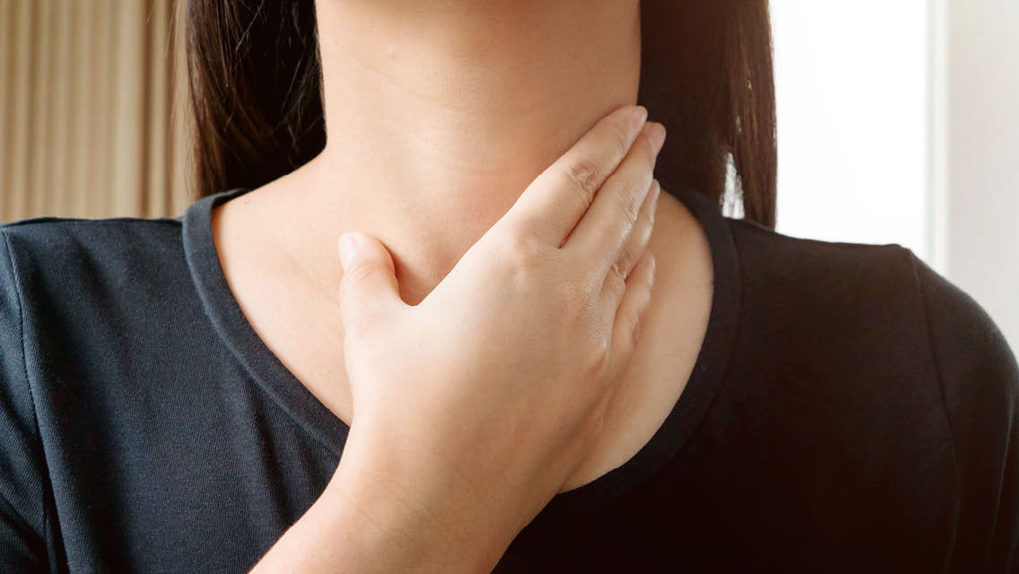 a woman holds her hand over her throat