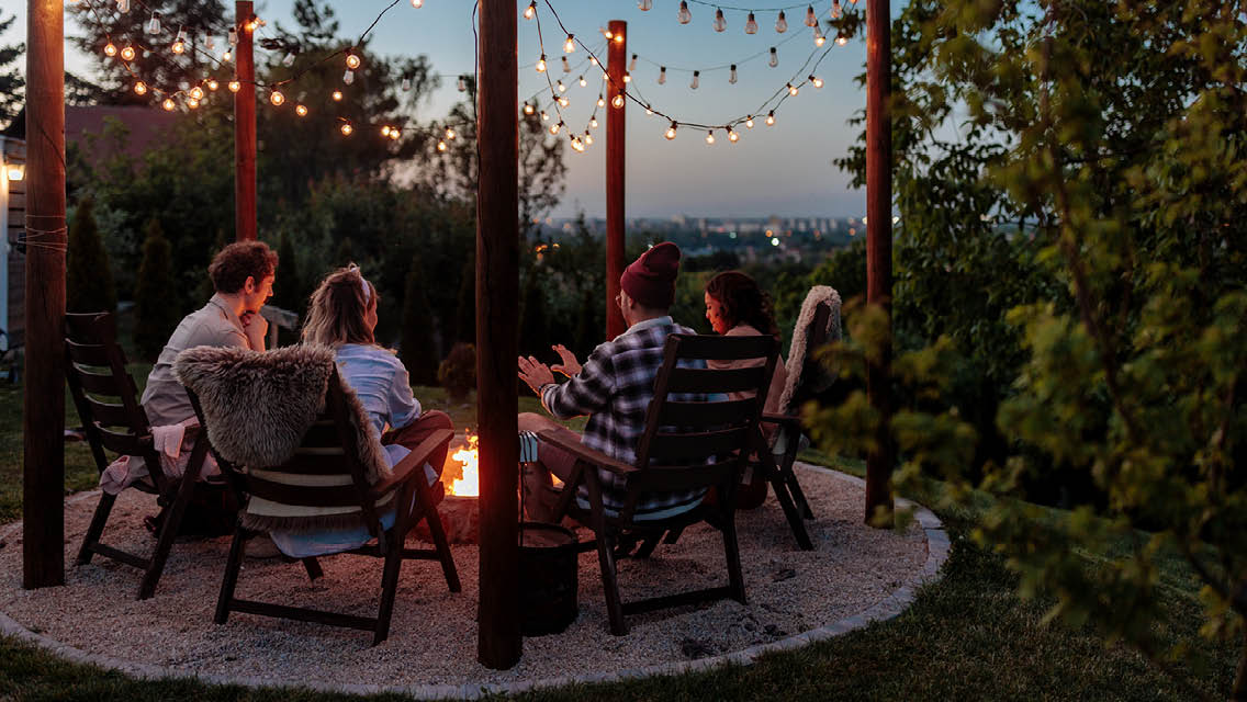 a group of friends sit around a fire at dusk