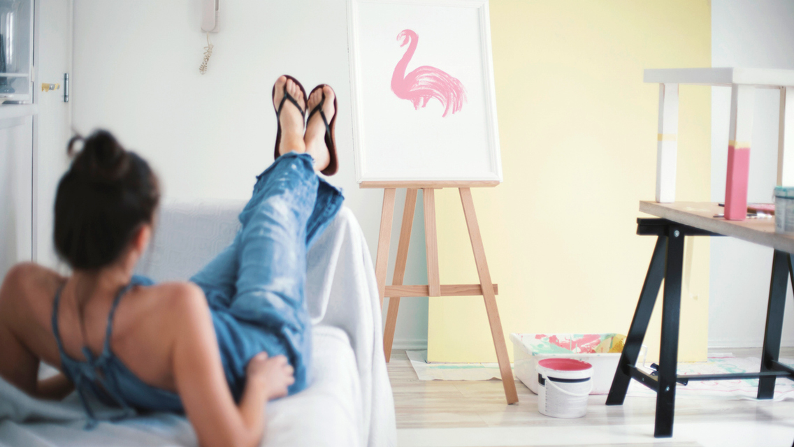 a woman sits and looks at a half finished painting
