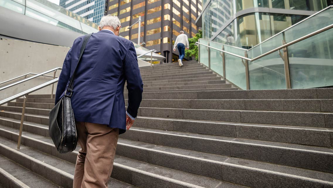 a senior man walks up a set of urban stairs