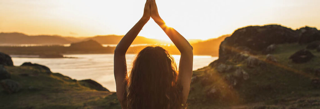 a person meditating out side at sunset.