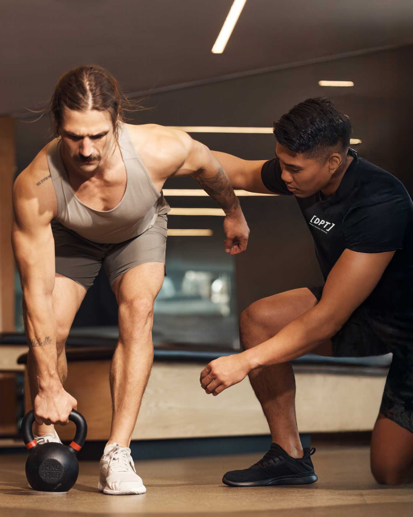 A Dynamic Personal Trainer instructing a client whose performing an exercise with a kettlebell.