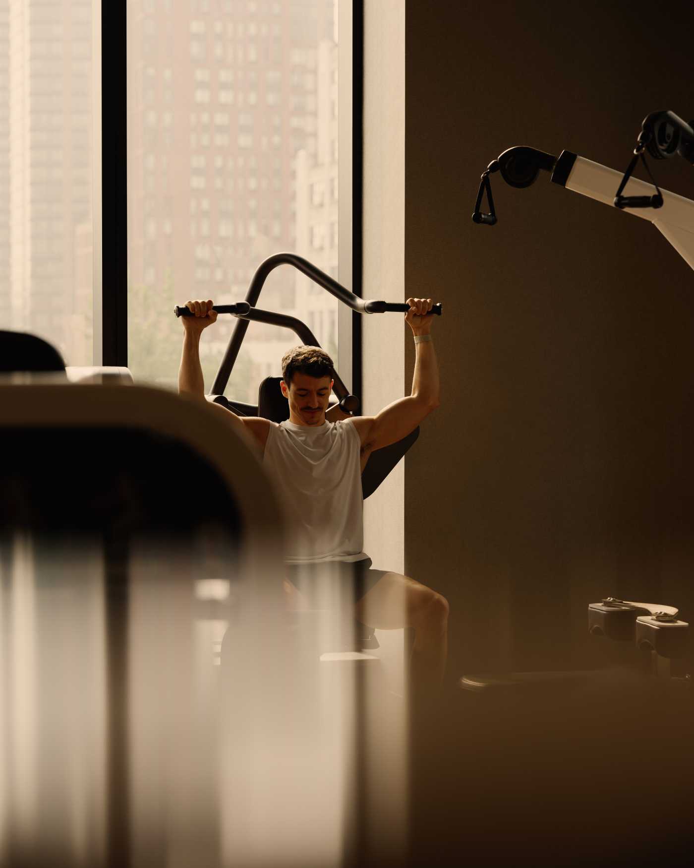 A man using an overhead press machine on the workout floor at Life Time.