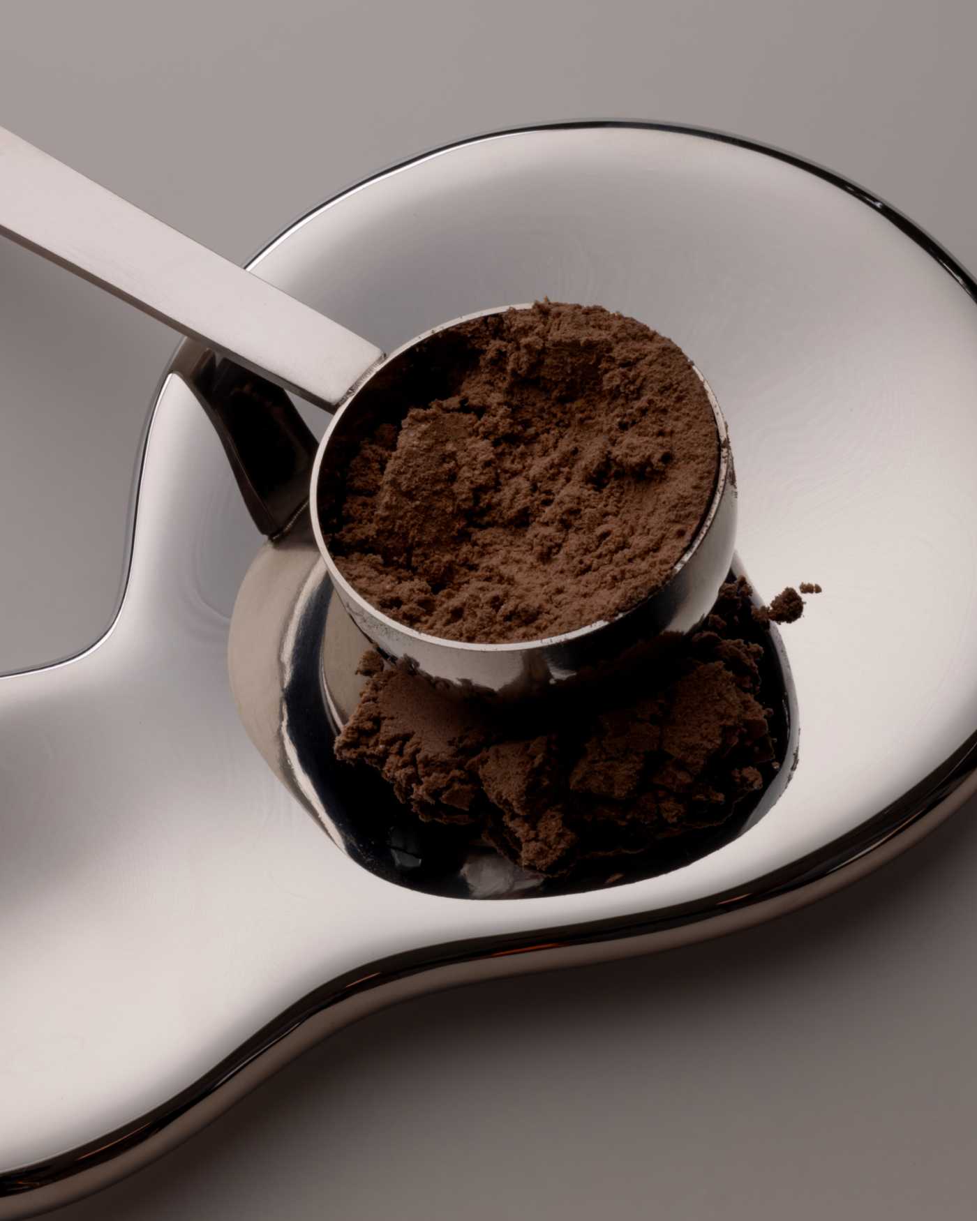 A scoop filled with dark protein powder.