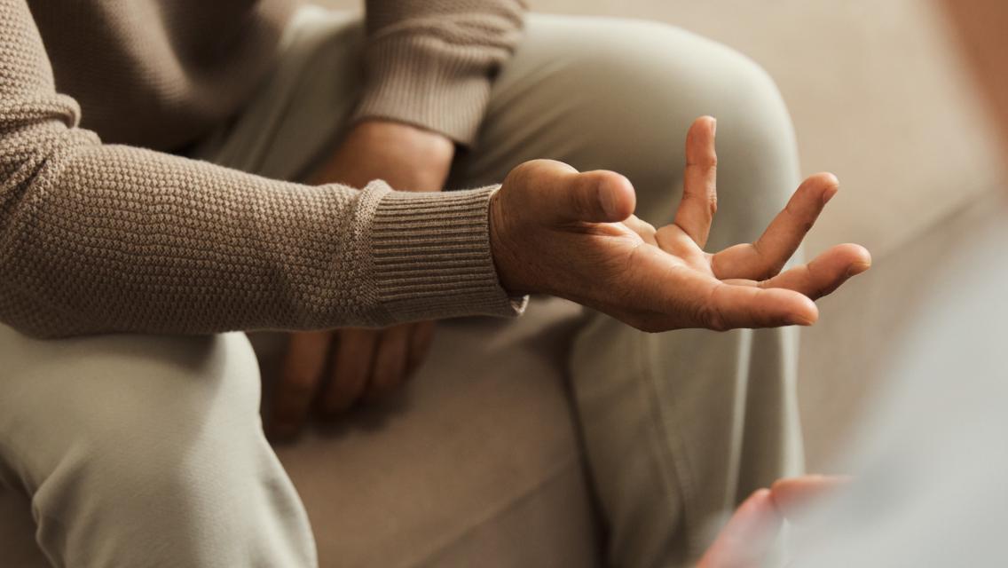 A close up of someone's hands as they're sitting on a couch talking to a medical provider.