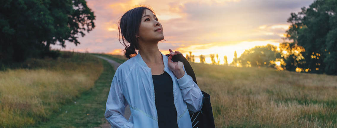 a woman walks down a field path looking up