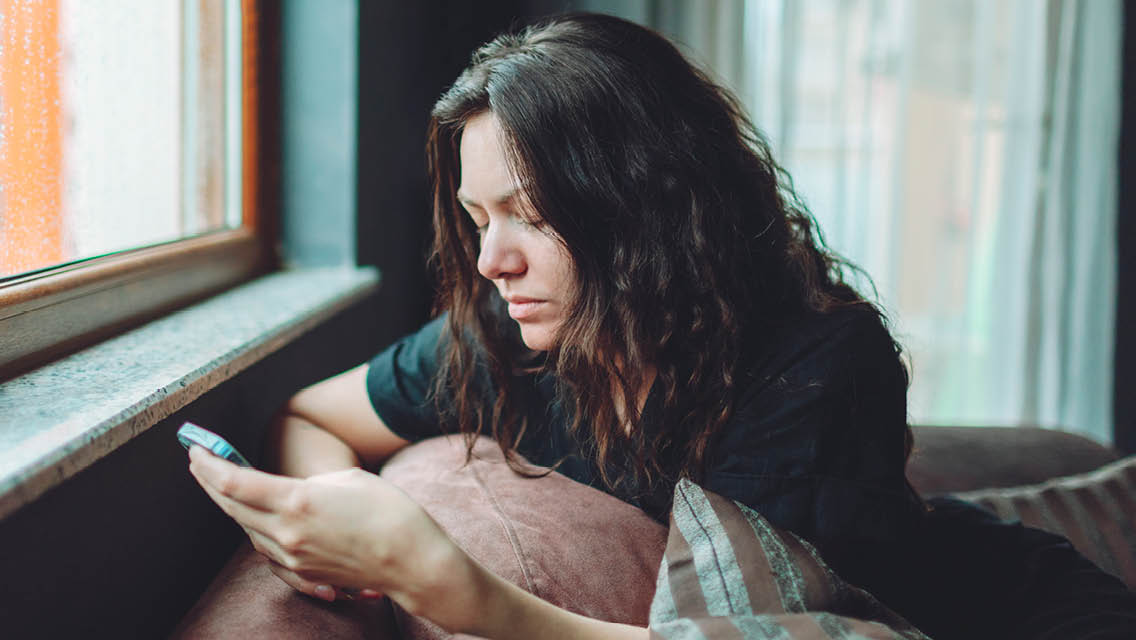 a woman looks dejected while looking at her phone