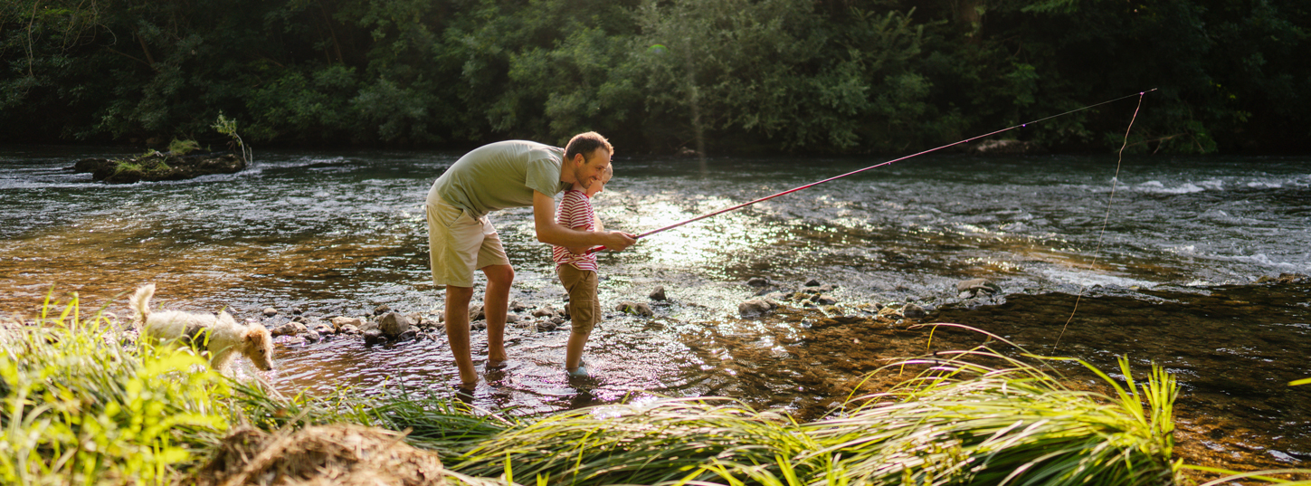 a father and son fish in stream