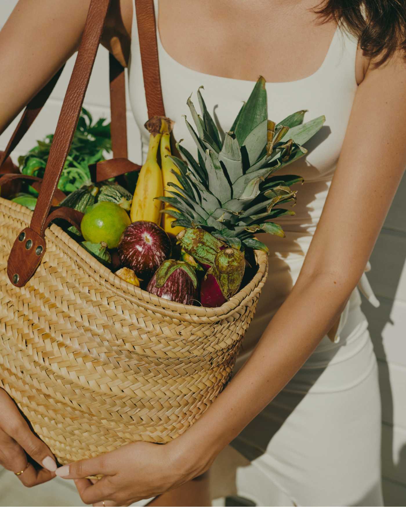 A woman holding a canvas bag full of fresh produce.