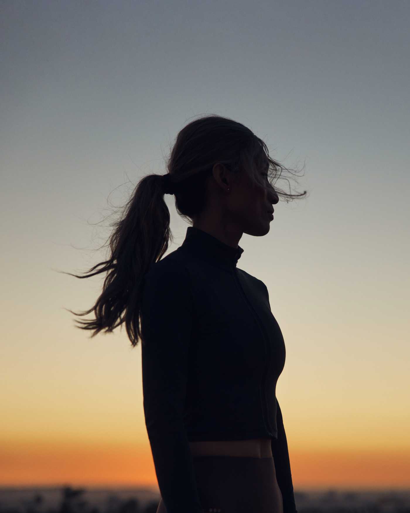 A silhouette of a woman with a sunset in the background.
