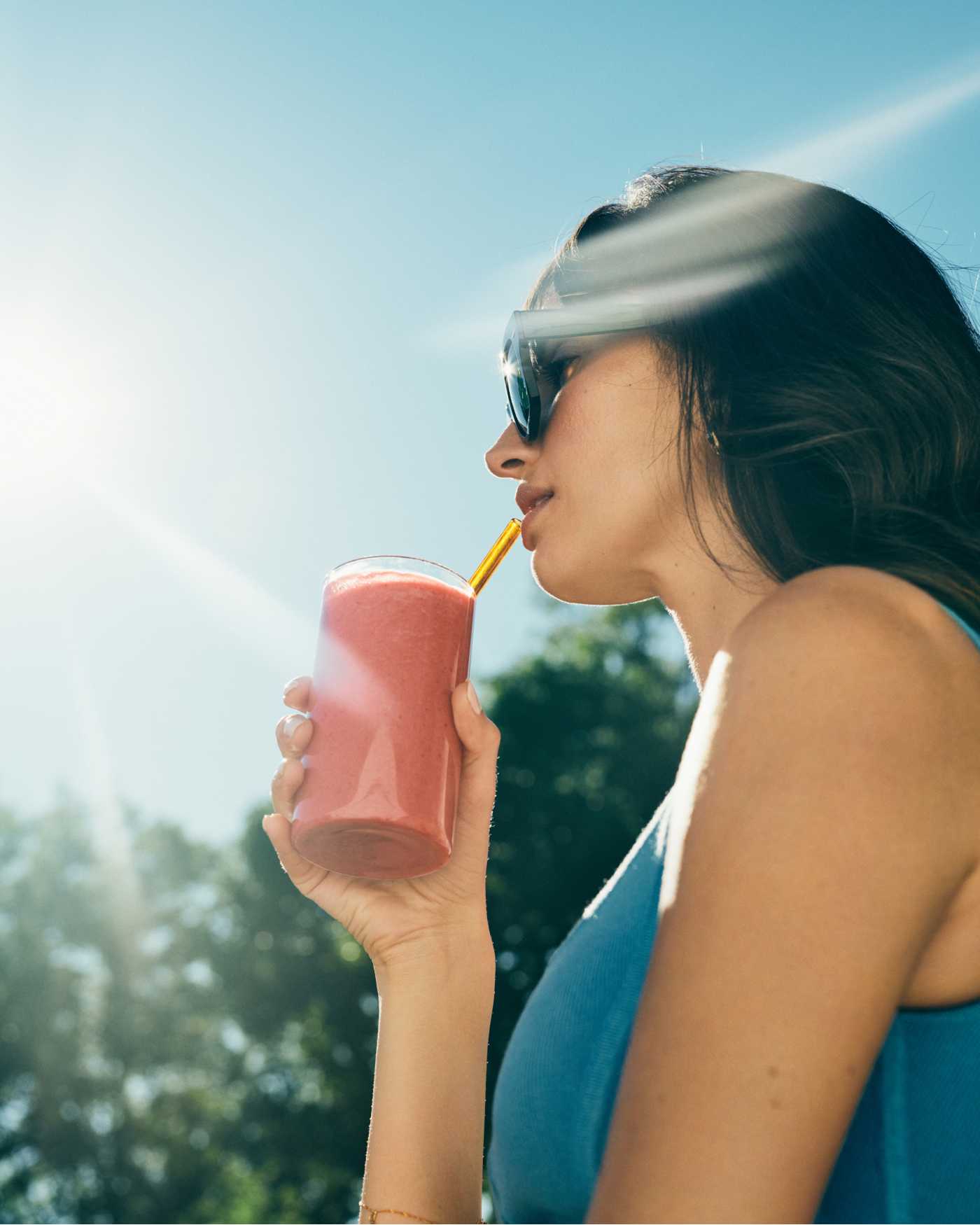 A woman sipping on a berry-colored shake.