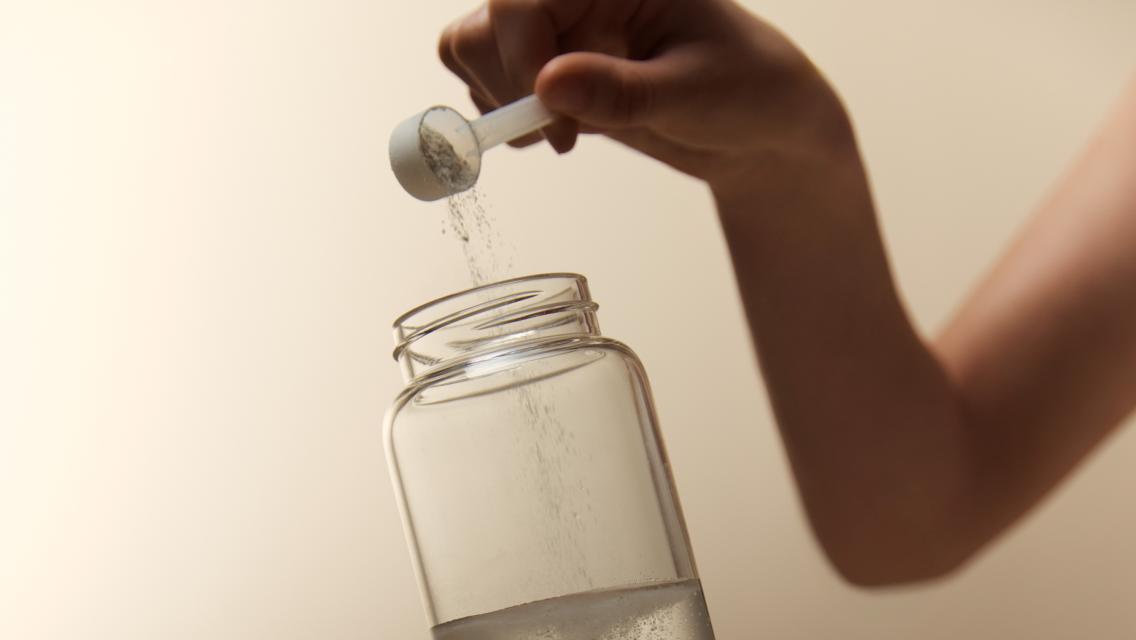 person scooping supplement into water