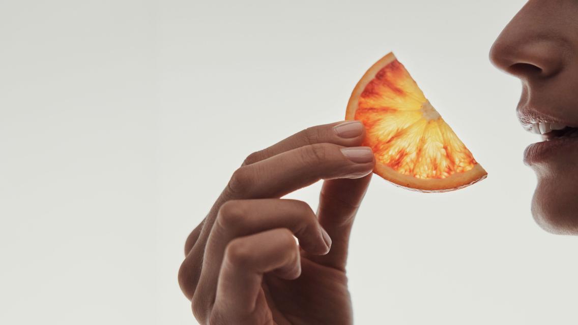A person lifting a piece of fruit to their mouth.