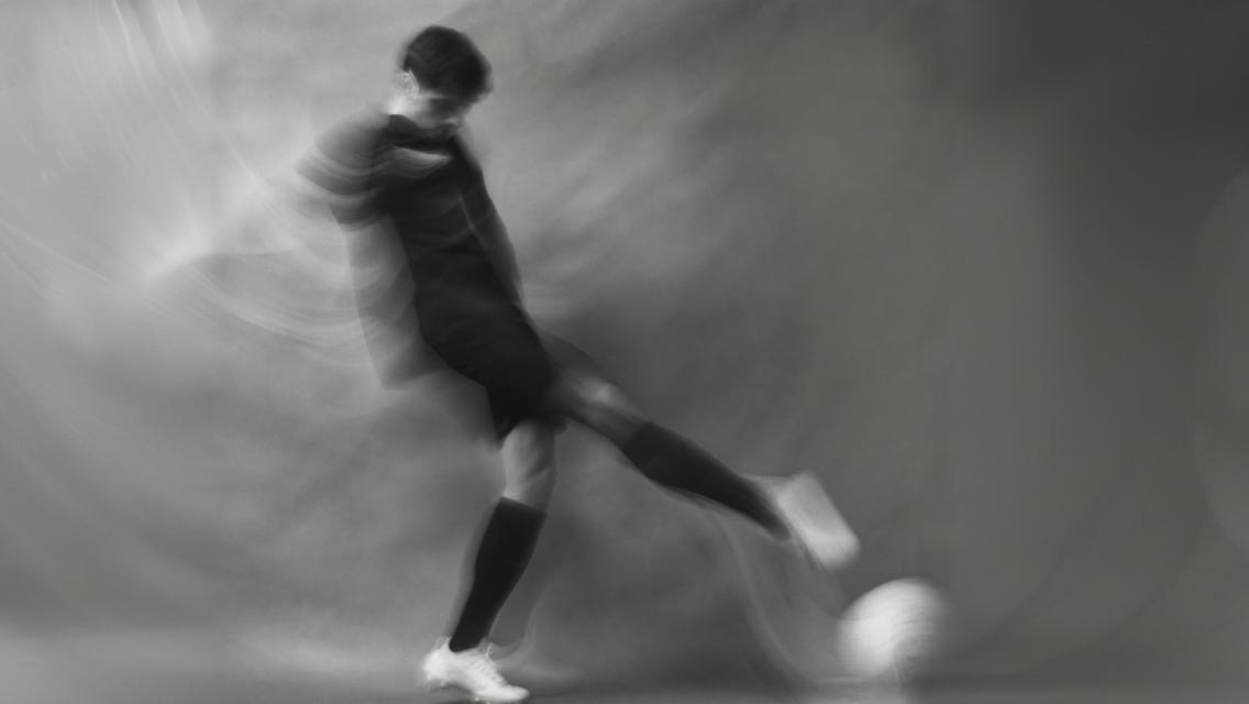 man kicking soccer ball