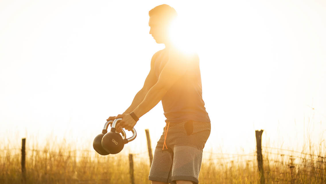 a man swinging kettlebells outside