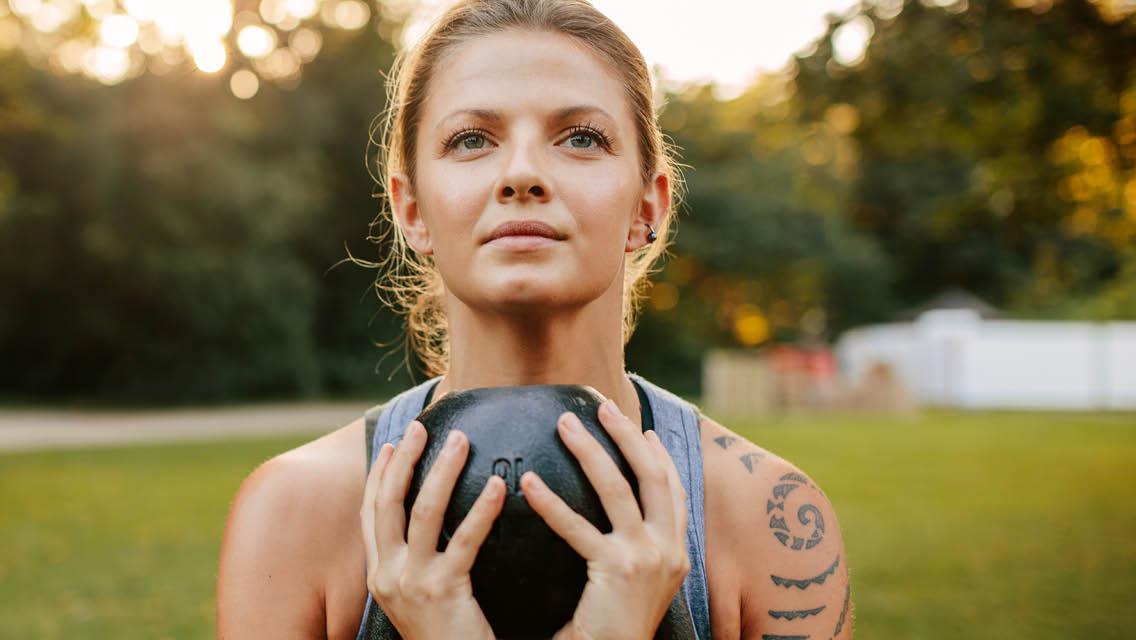 a woman holds a kettlebell