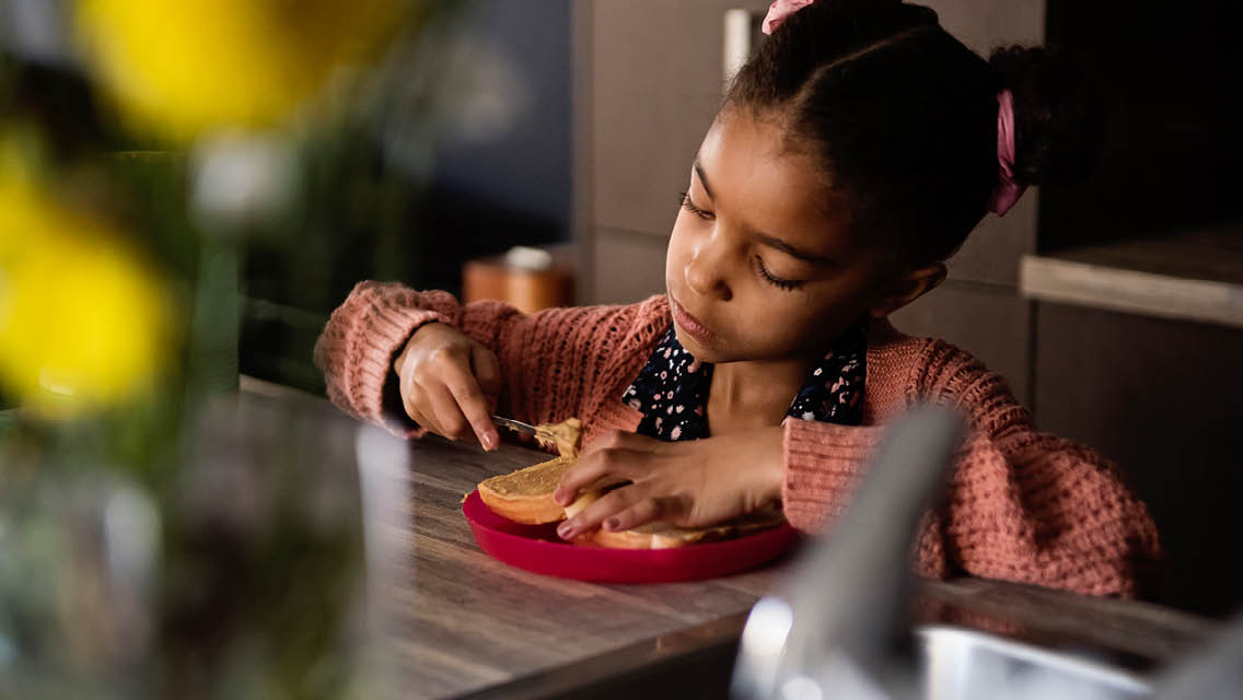 a young girl eats a peanut butter and jelly sandwich