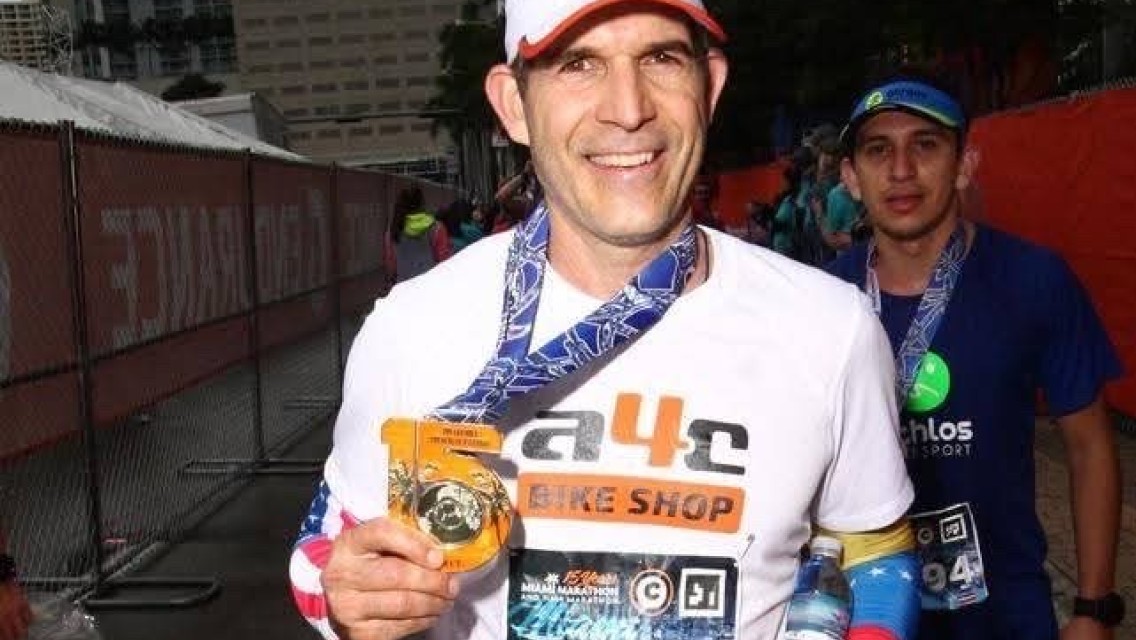 miami-runner Man smiling and holding a medal after finishing a race.