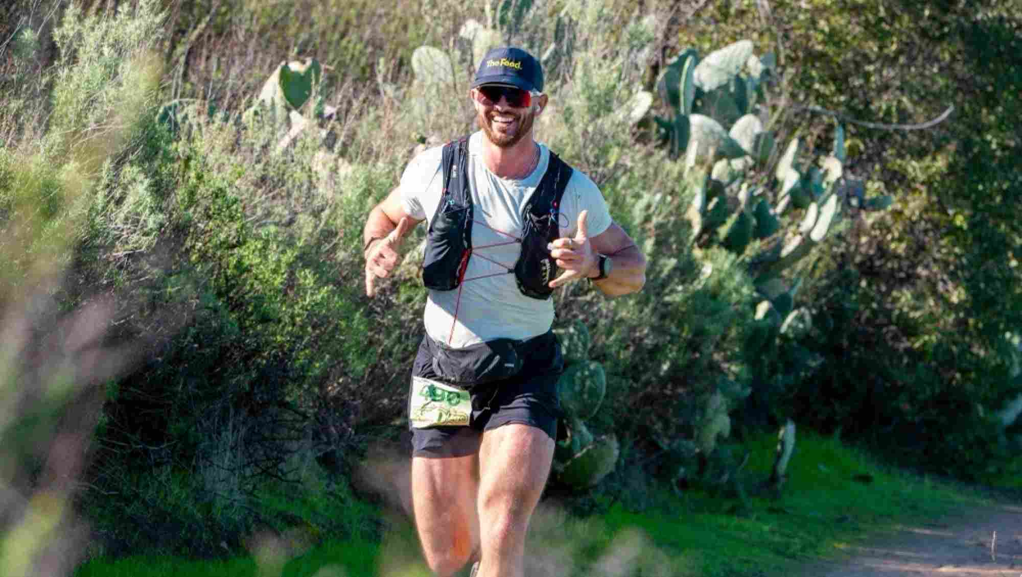 Nick running a race smiling and giving a thumbs up.