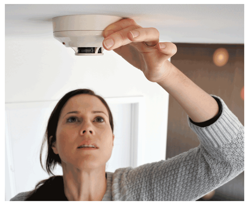 a woman checks her smoke detector