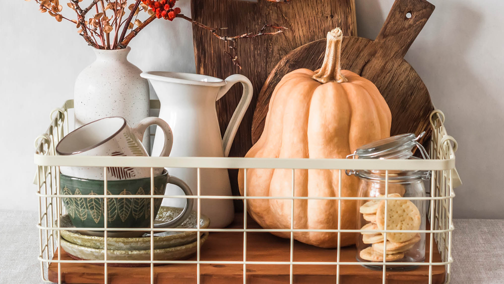 cute wire basket on a kitchen counter filled with dishes and a gourd