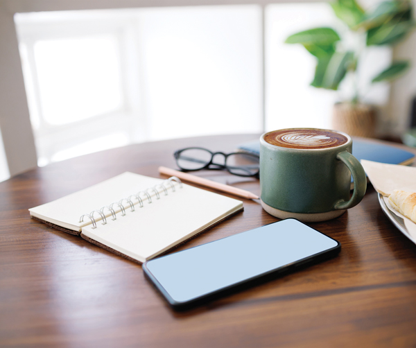 table with a journal, phone, pencil and cup of coffee