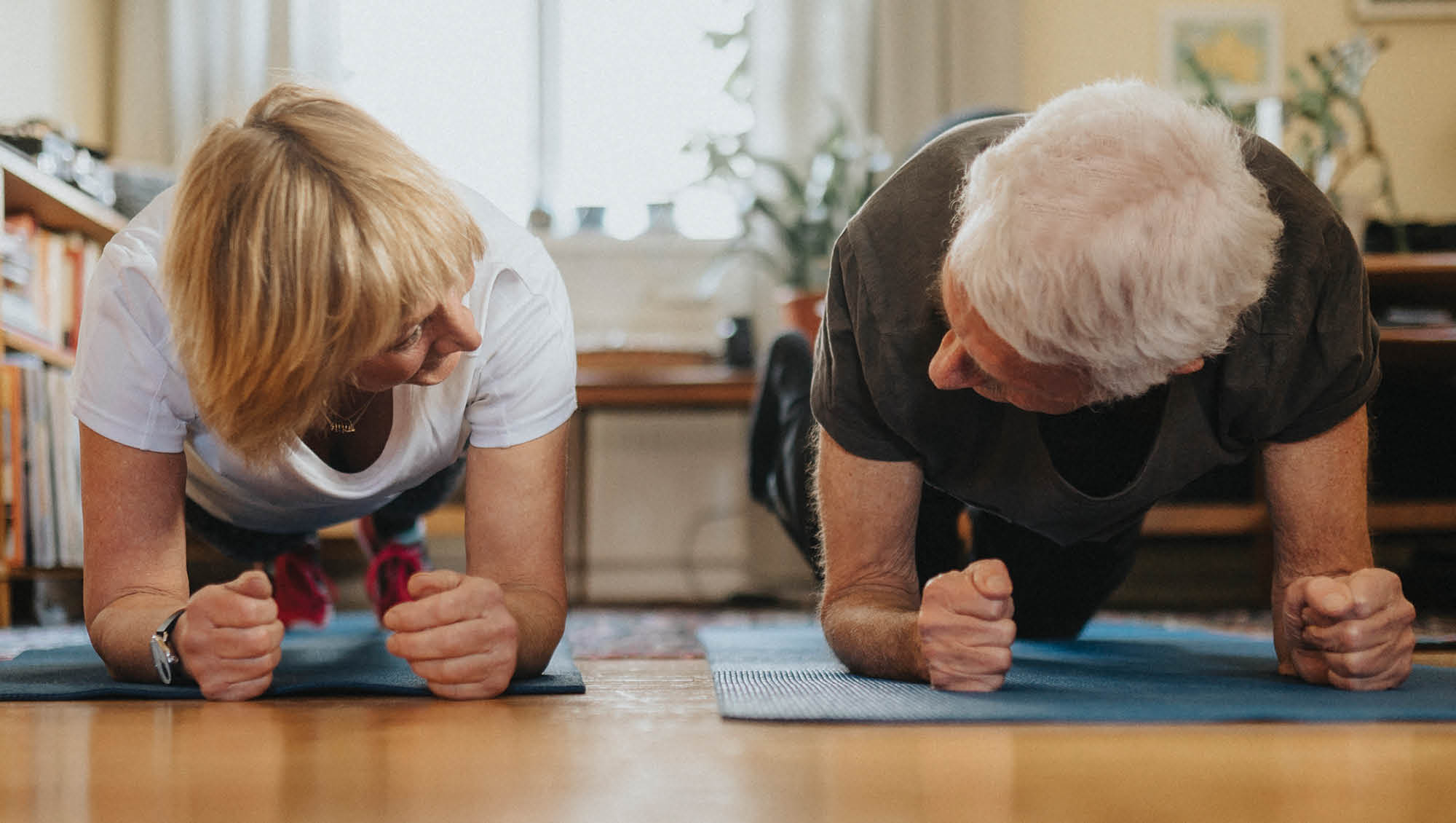 a couple holds a forearm plank in their living room