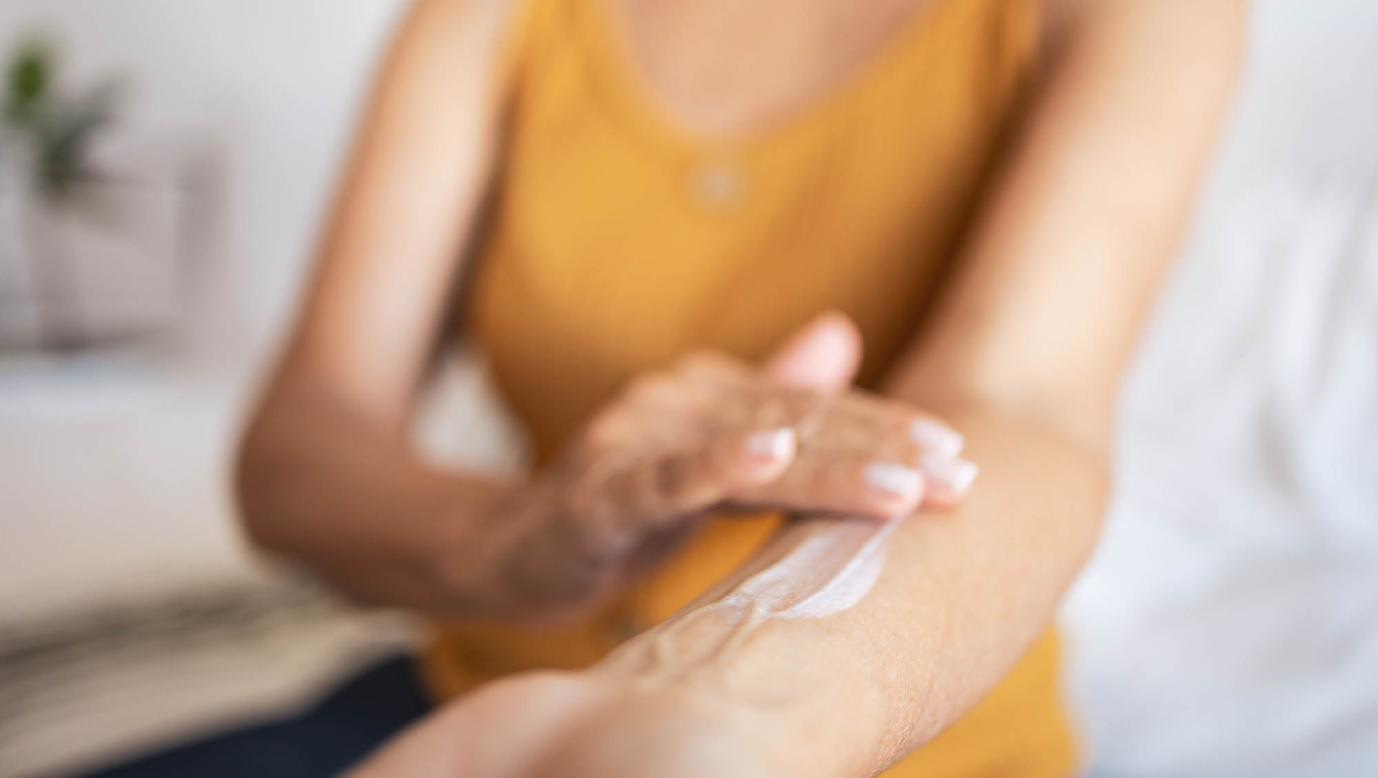 a woman rubs hormone lotion on her arm