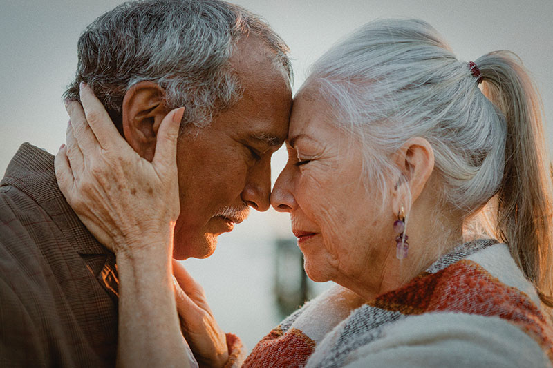 a senior couple holds their foreheads together