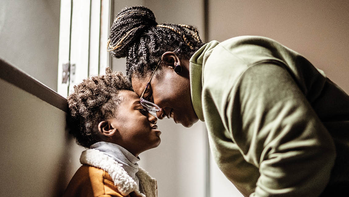 a woman and son stand with their foreheads together