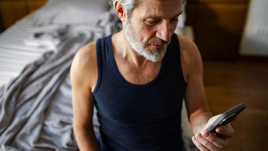 a senior man looks at his phone