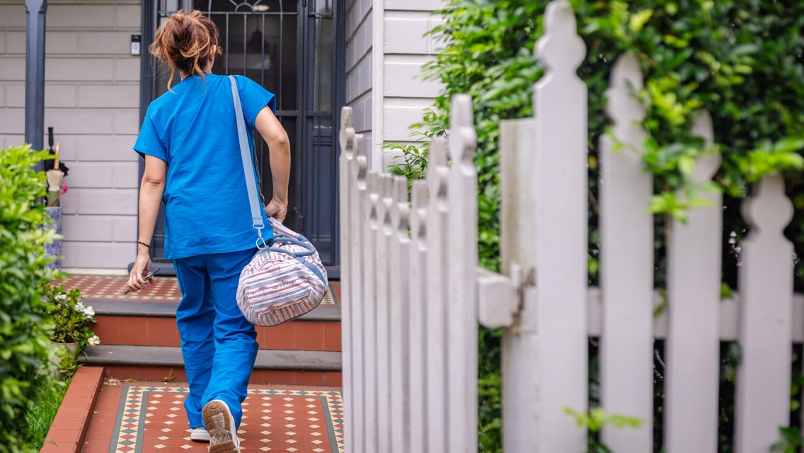a person wearing scrubs walks into a home