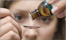 Dripping herbal essence of a vial over a spoon