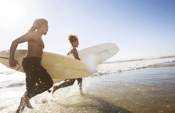 Ethnic couple running through the surf