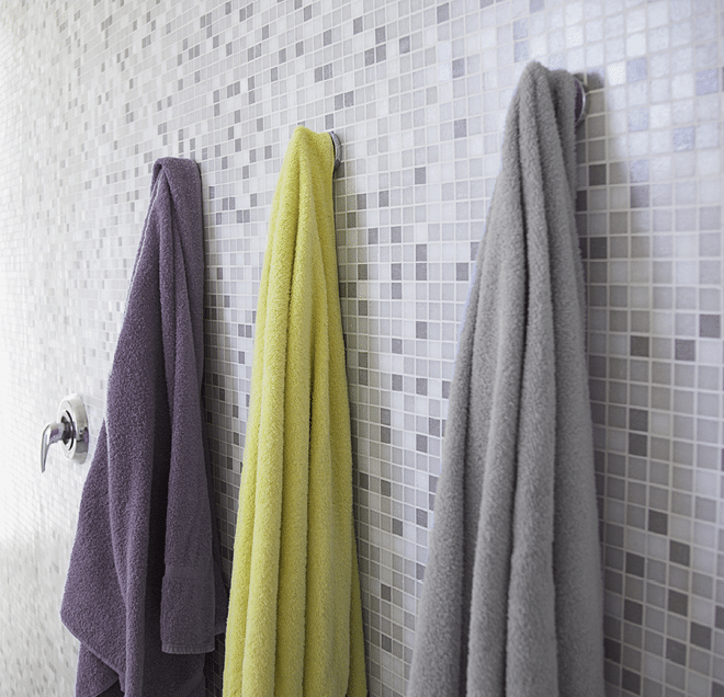 Gray tiled shower stall with three hanging towels --- Image by � Whisson/Jordan/Corbis