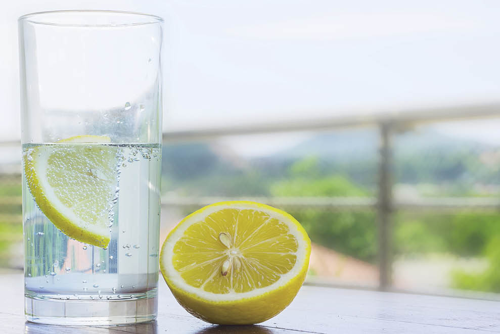 Glass of water with lemon isolated on white background