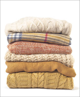 Stack of various sweaters isolated on white background