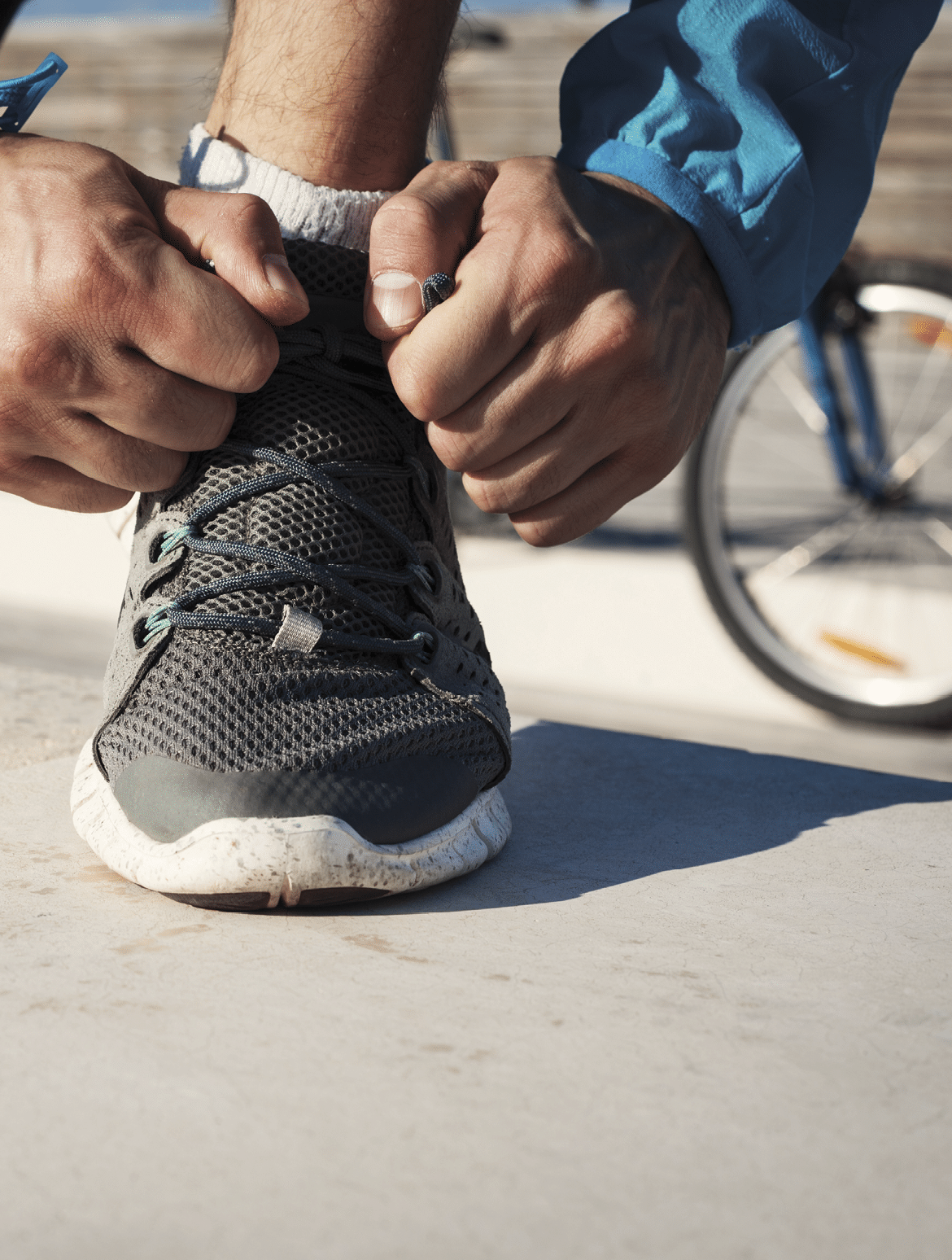 preparation of sportsman tie shoelaces on his running shoe and mountain bicycle at background