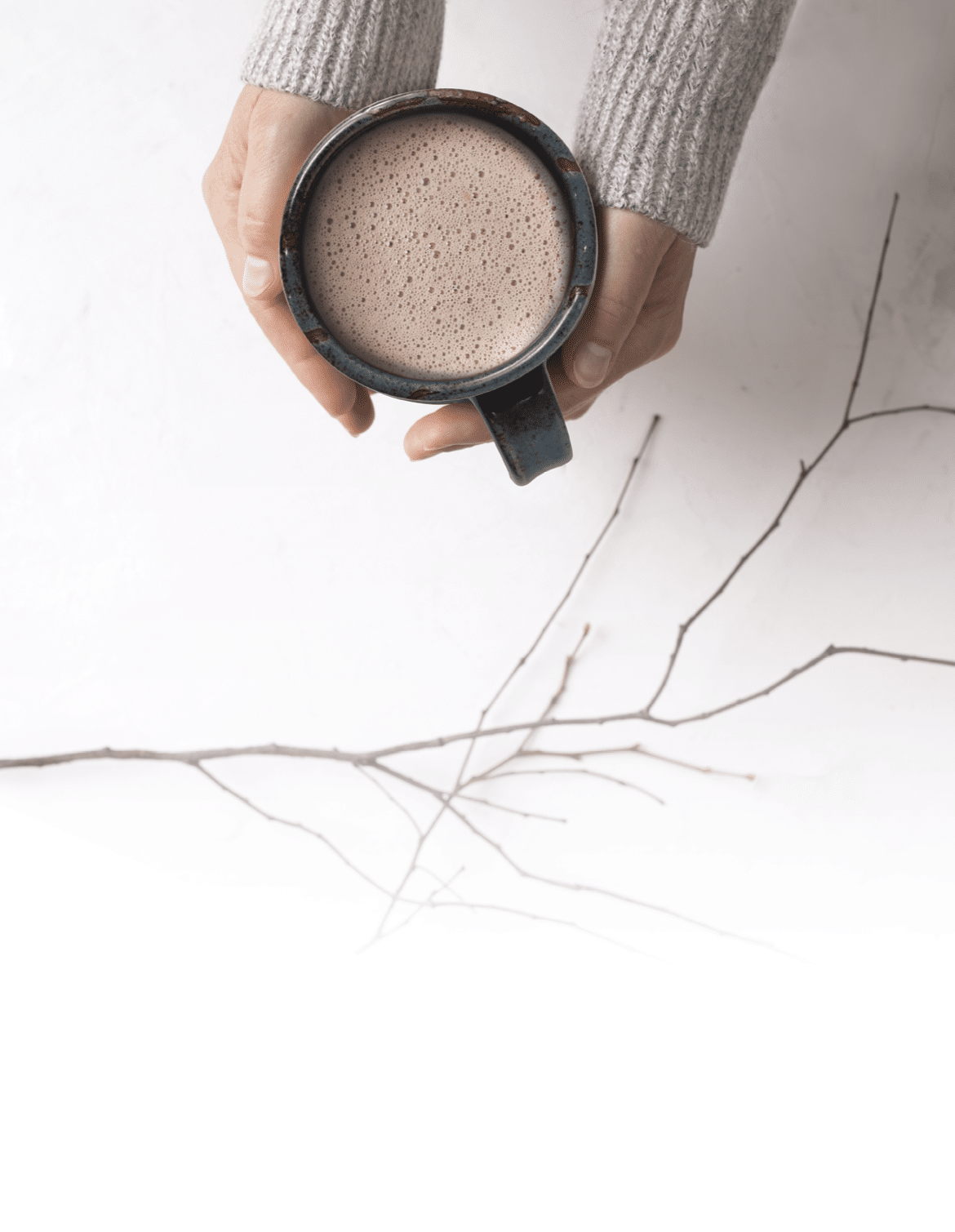 Overhead view of woman holding mug of hot chocolate over  gray autumn background