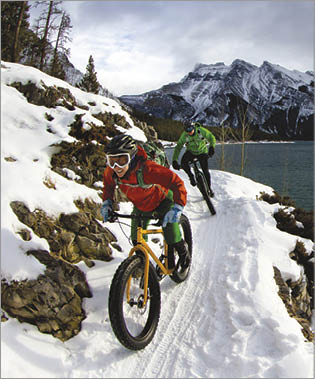 A woman and man enjoy a winter fat bike ride in Banff National Park, Alberta, Canada 