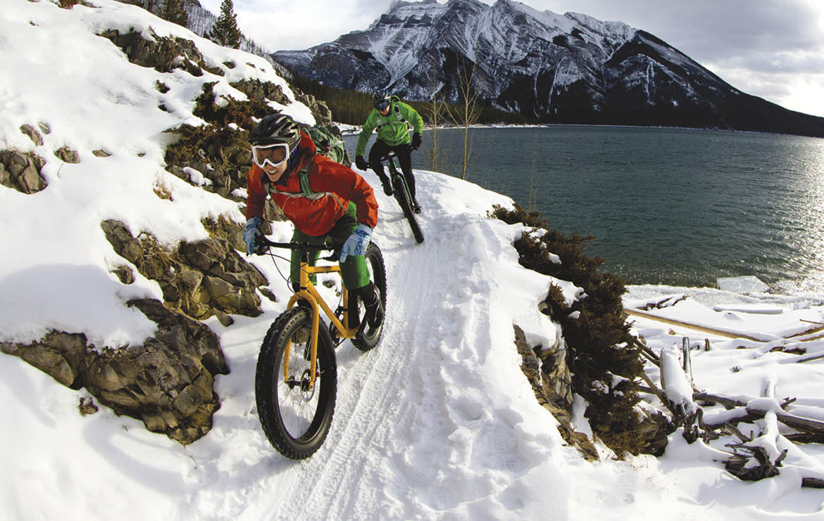 A woman and man enjoy a winter fat bike ride in Banff National Park, Alberta, Canada 