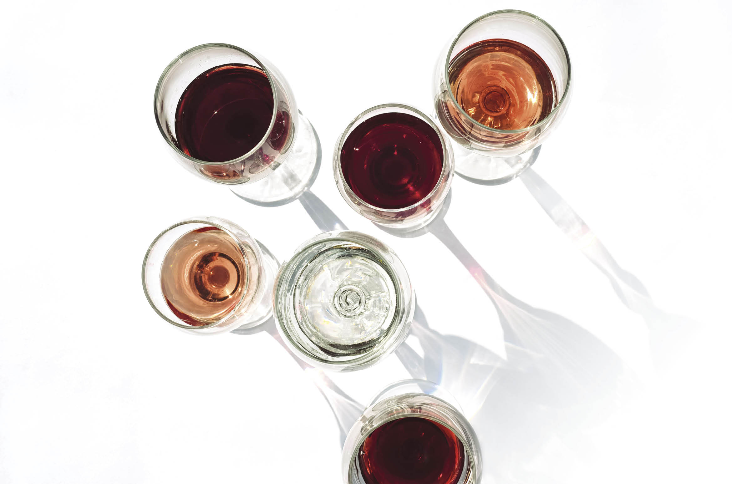Wine of different varieties in glasses on a white background  Fashionable hard shadows from glasses 