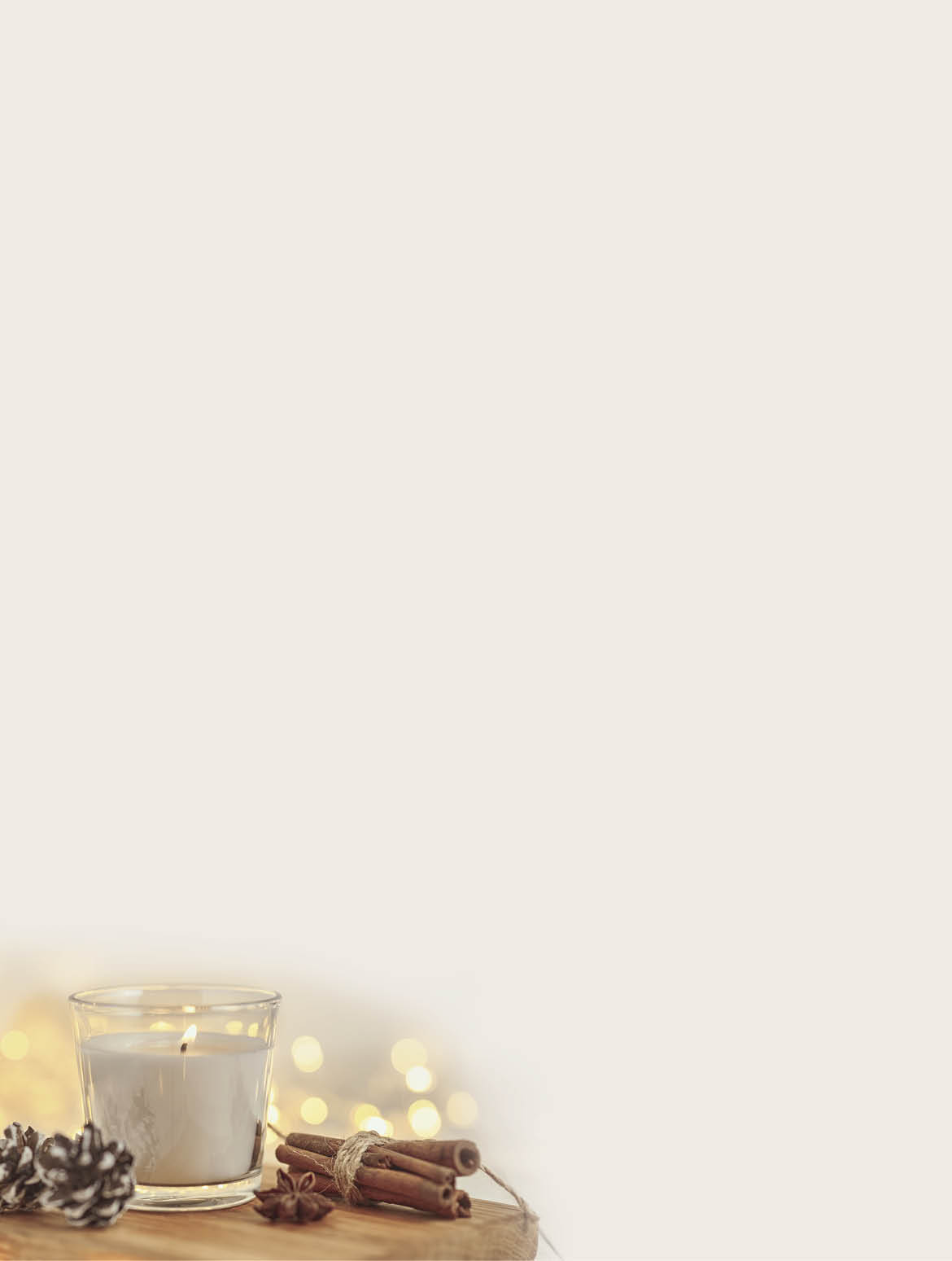 White burning candle with decorations and garland lights in bokeh on wooden table  Cozy home and hygge concept