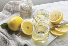 Fresh lemon and glasses of lemon water on white rustic  wooden table top  Vintage style  Still life  Food styling shot 